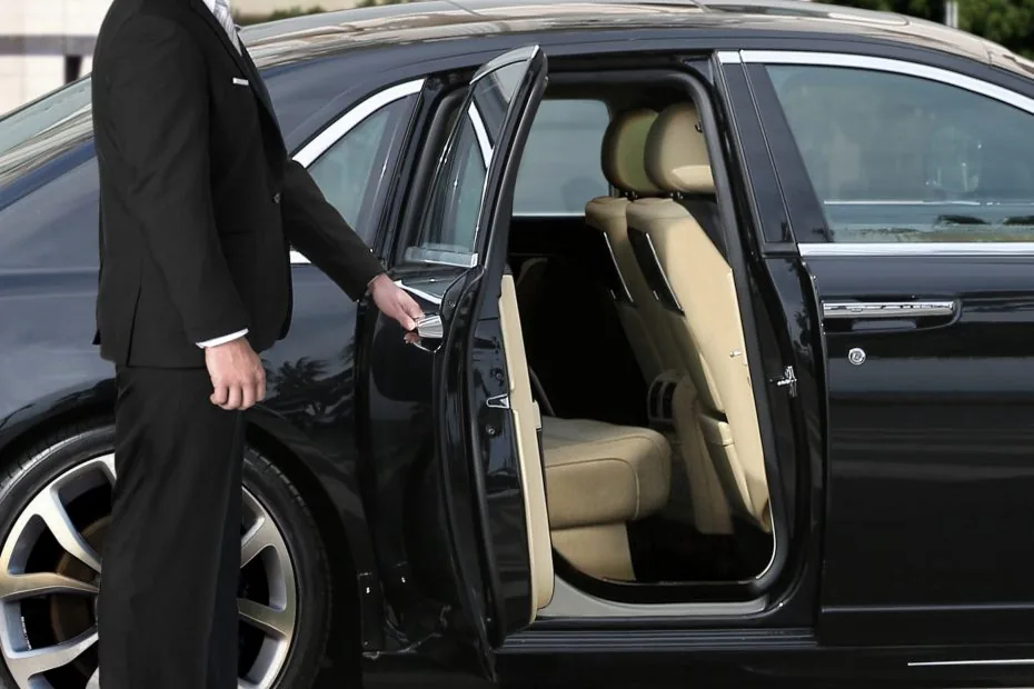 Chauffeur professionnel ouvrant la porte d’une berline noire